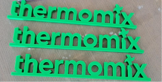 Green and white 'thermomix' branding on a wooden surface